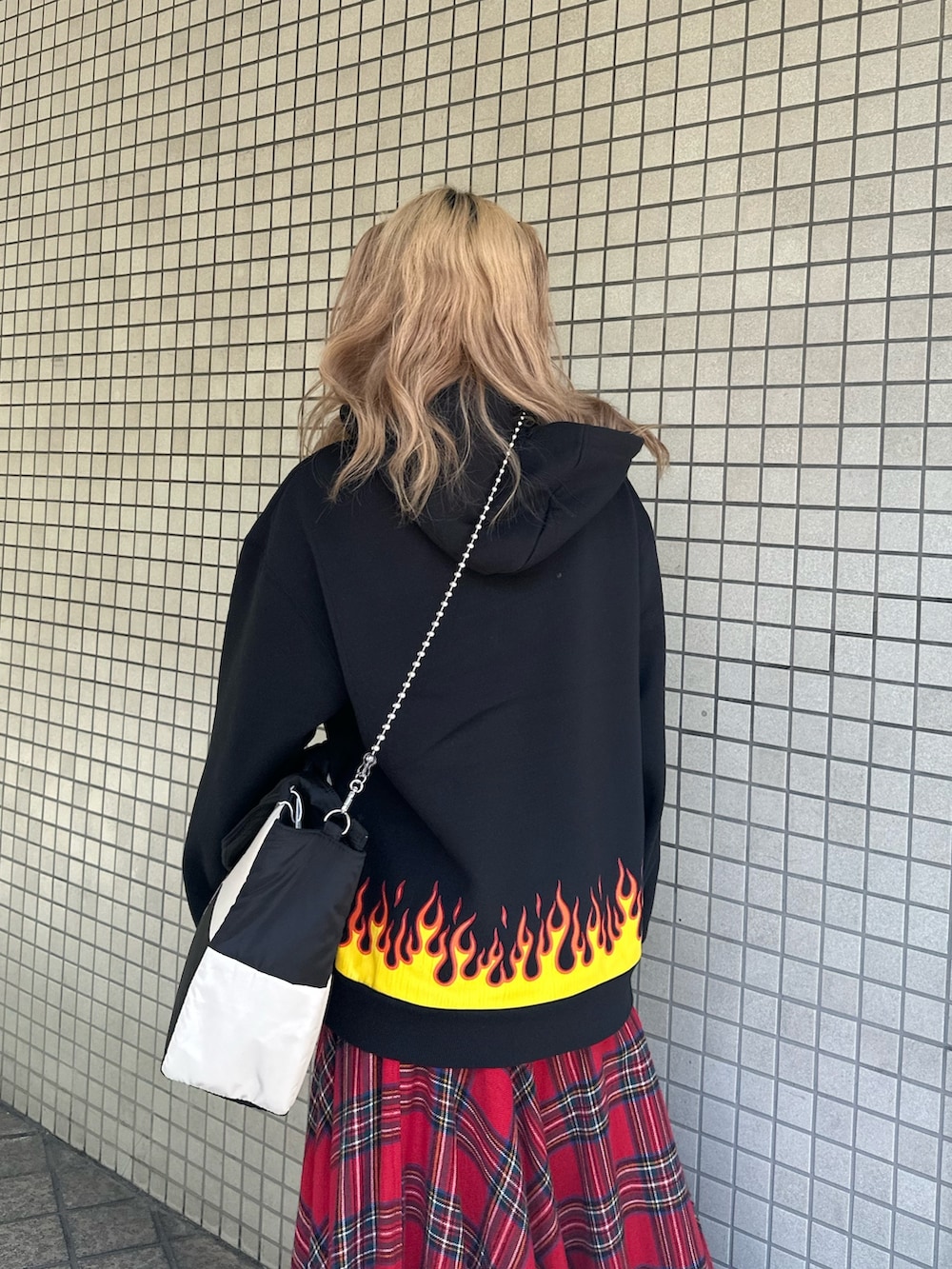 レッド系のスカート、ブラック系のパーカー、ブラック系のハンドバッグを着用したレディースの秋コーディネートの5枚目の写真