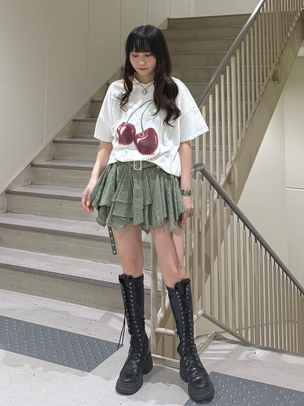 ホワイト系のTシャツ/カットソー、ブラック系のブーツ、グリーン系のスカートを着用したレディースの春コーディネートの5枚目の写真
