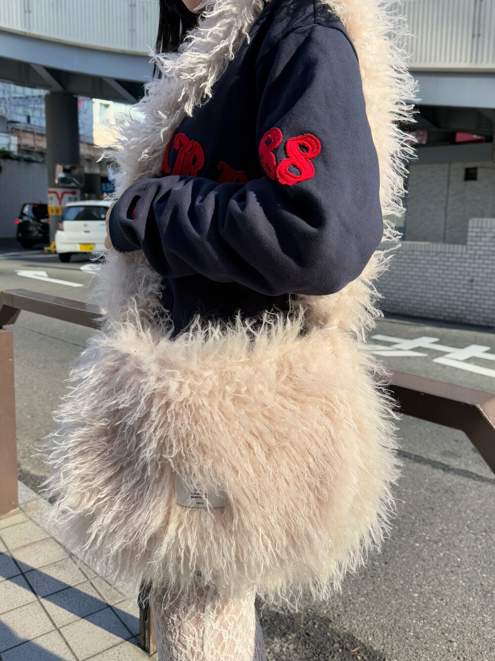 ブルー系のパーカー、ホワイト系のショルダーバッグ、ブラック系のスカートを着用したレディースの冬コーディネートの7枚目の写真