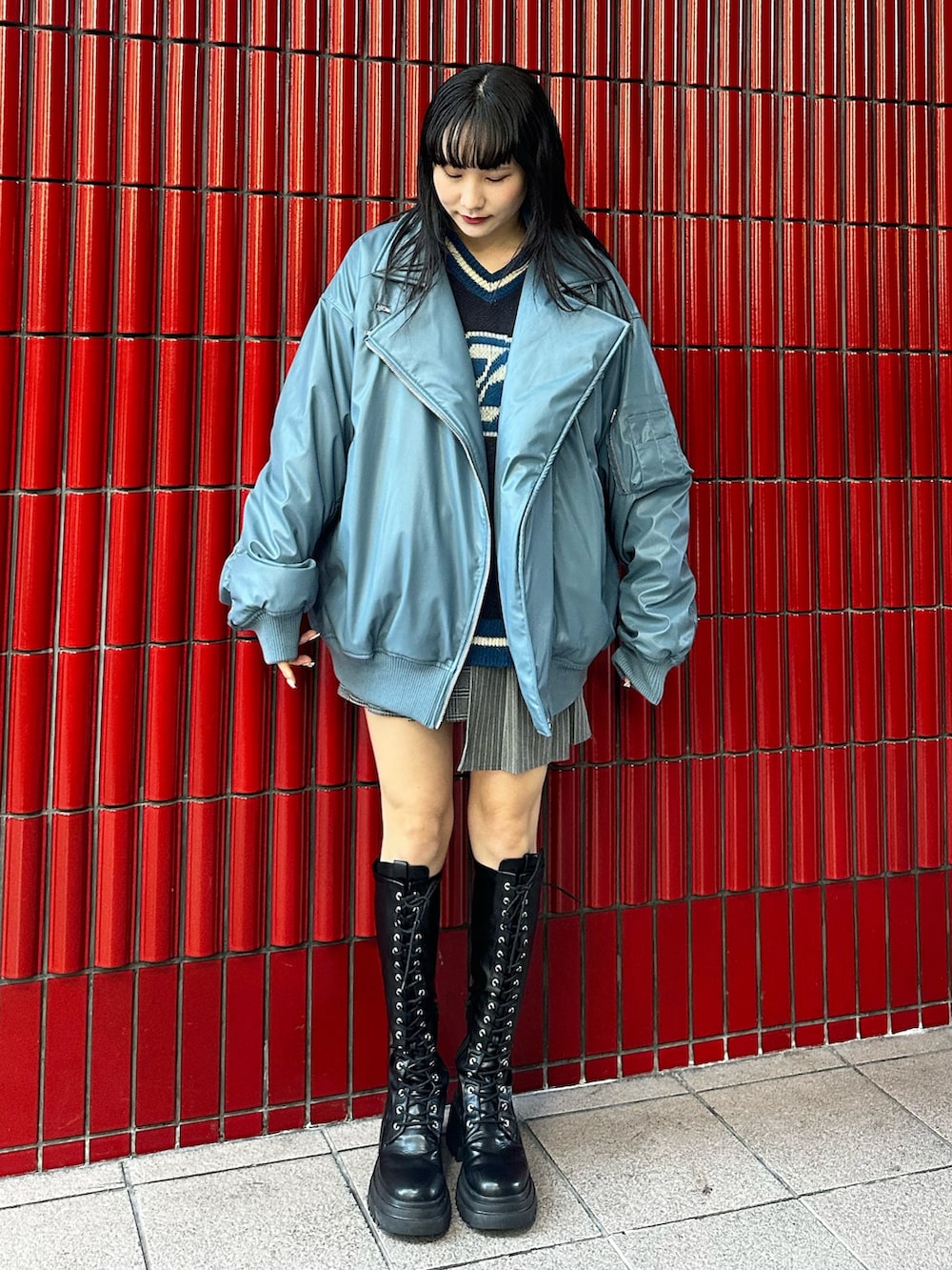 グレー系のスカート、ブラック系のブーツ、ブルー系のブルゾンを着用したレディースの秋コーディネートの2枚目の写真