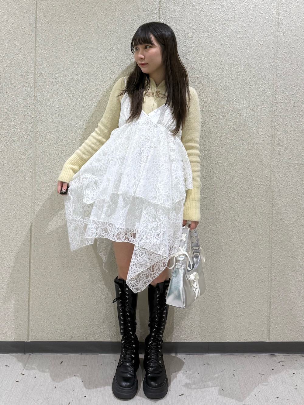 イエロー系のパーカー、ホワイト系のワンピース、シルバー系のハンドバッグを着用したレディースの冬コーディネートの2枚目の写真