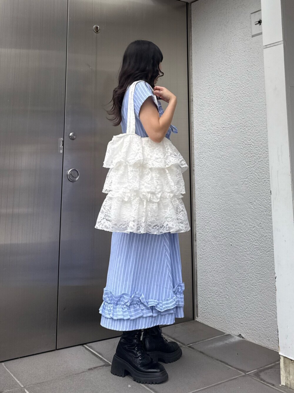 ブラック系のブーツ、ブルー系のワンピース、ホワイト系のトートバッグを着用したレディースの春コーディネートの3枚目の写真