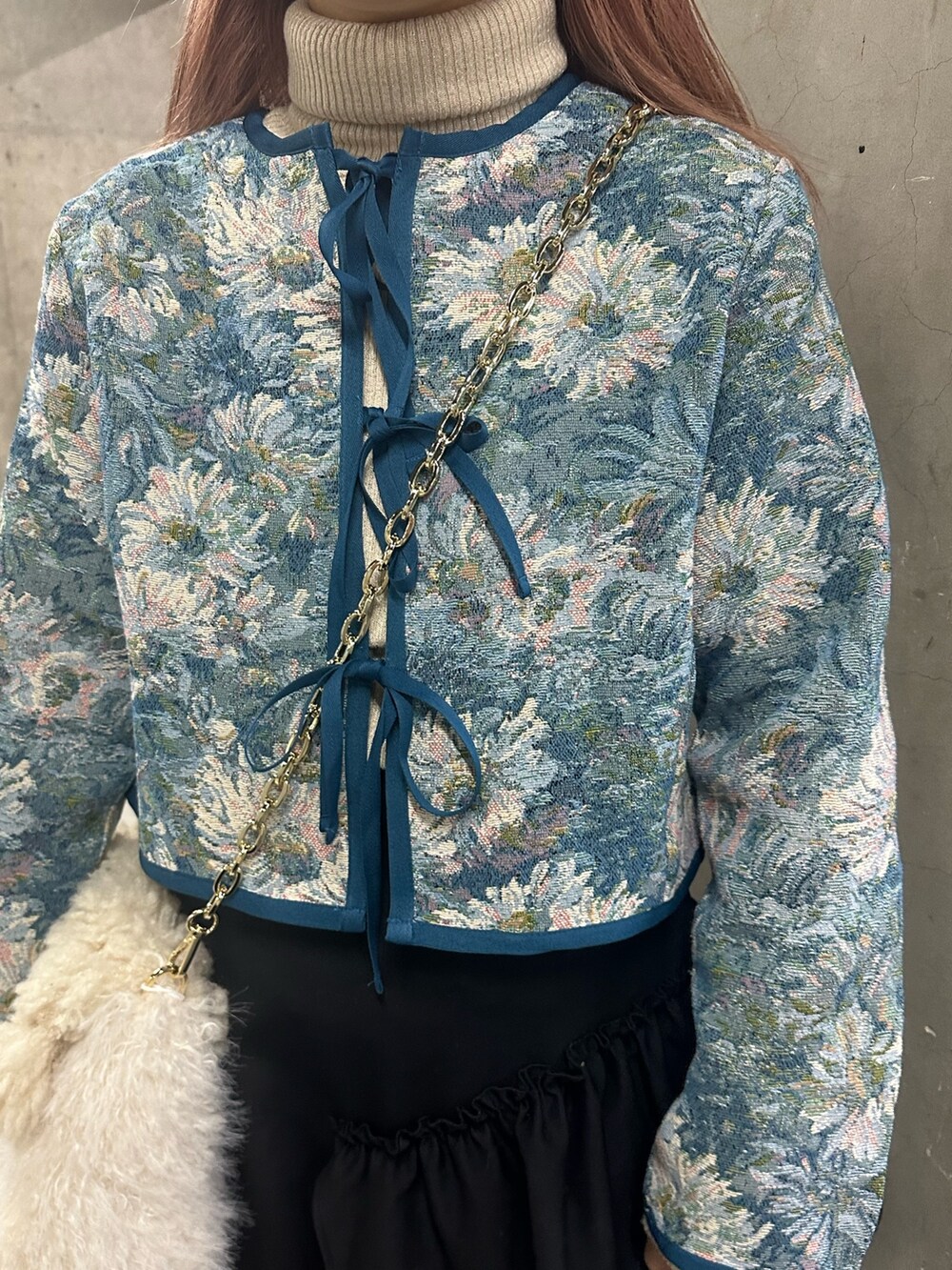 ブラック系のスカート、ブルー系のノーカラージャケット、ホワイト系のハンドバッグを着用したレディースの冬コーディネートの6枚目の写真