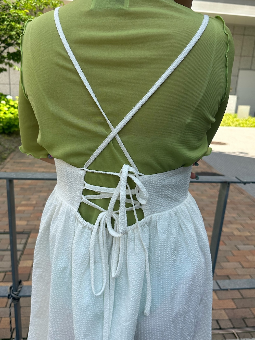 シルバー系のハンドバッグ、ブラック系のブーツ、ホワイト系のワンピースを着用したレディースの春コーディネートの5枚目の写真