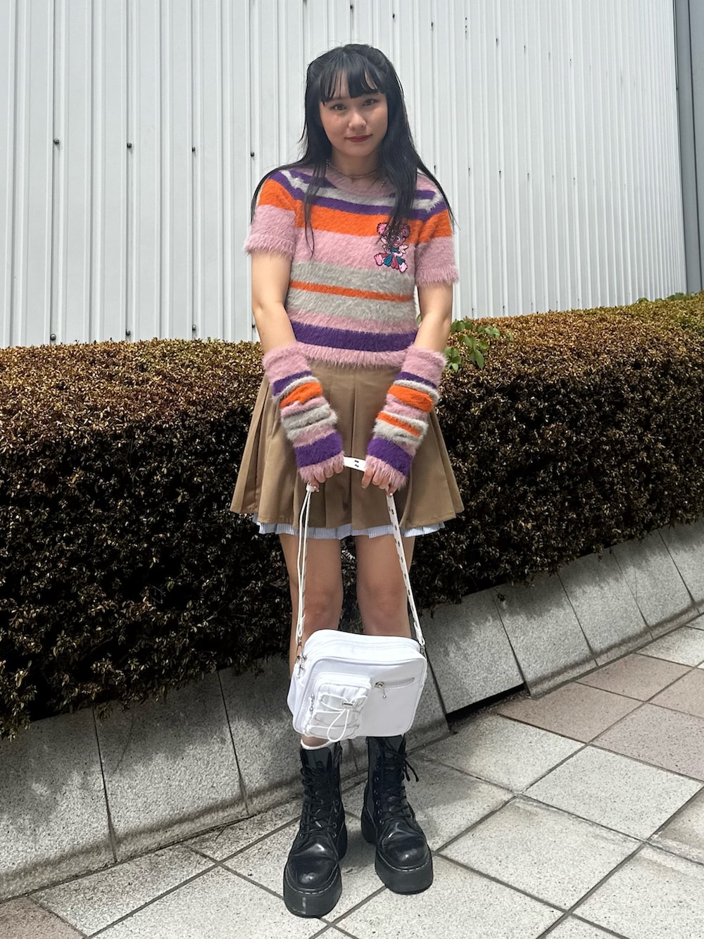 ピンク系のニット/セーター、ベージュ系のスカート、ホワイト系のショルダーバッグを着用したレディースの夏コーディネートの2枚目の写真