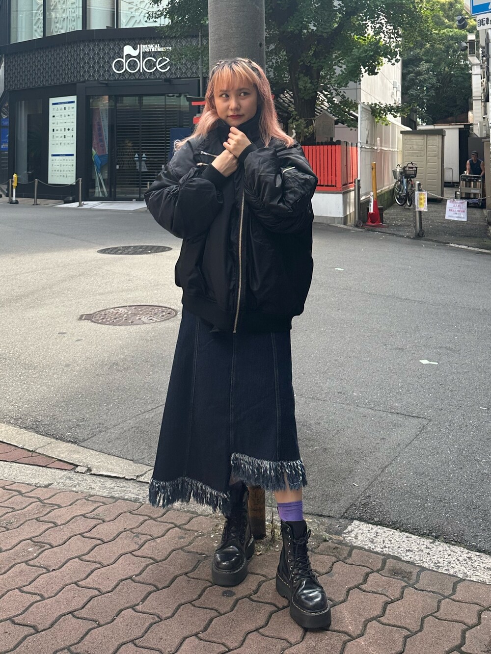 ブルー系のジャンパースカート、ホワイト系のニット/セーター、ブラック系のMA-1を着用したレディースの夏コーディネートの2枚目の写真