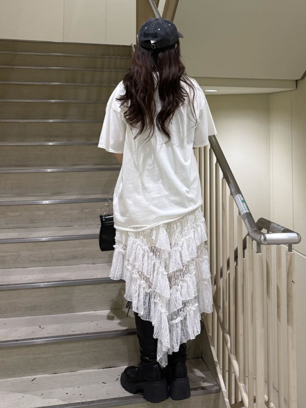 ブラック系のブーツ、ホワイト系のTシャツ/カットソー、ブラック系のハンドバッグを着用したレディースの春コーディネートの3枚目の写真