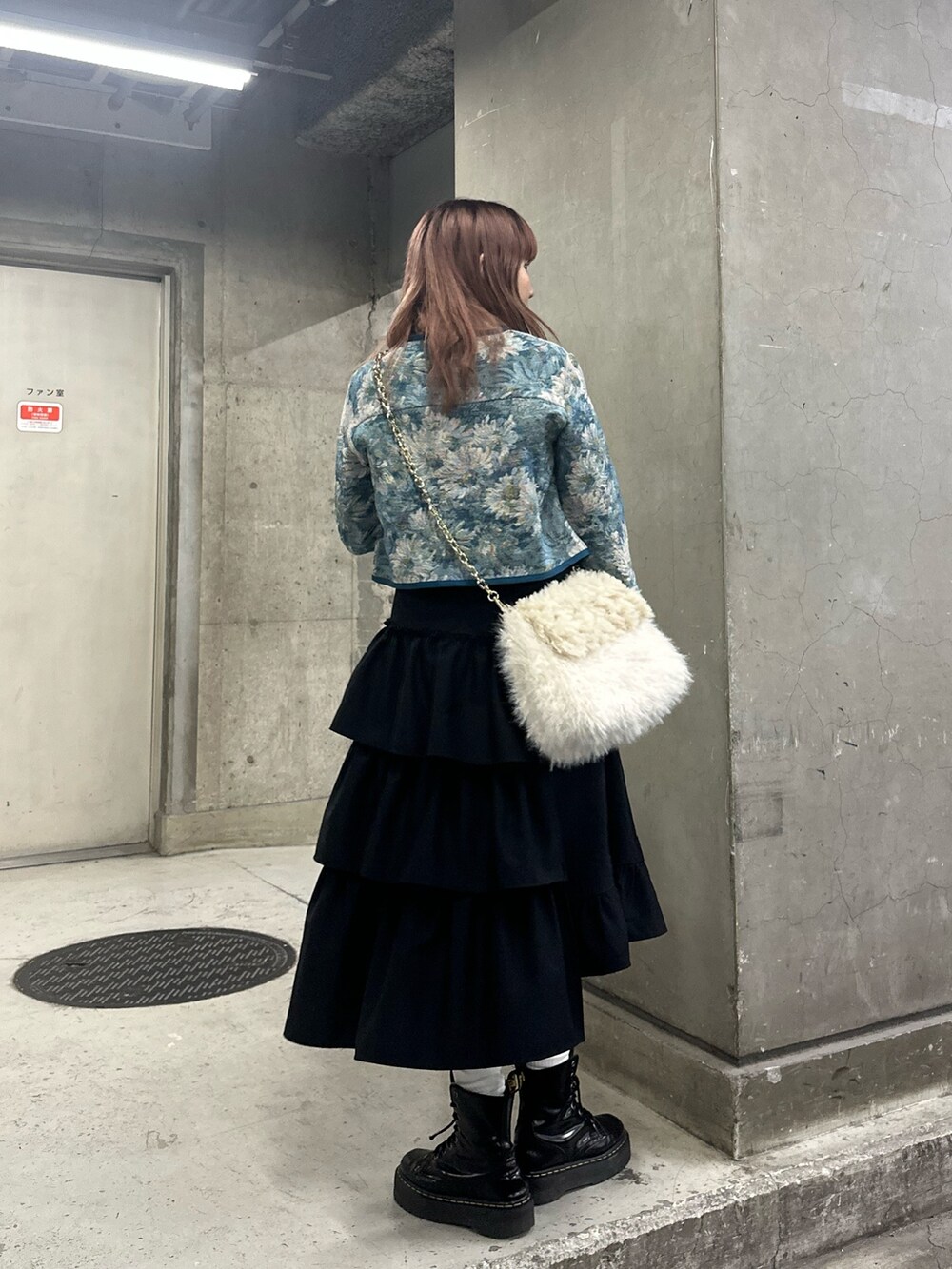 ブラック系のスカート、ブルー系のノーカラージャケット、ホワイト系のハンドバッグを着用したレディースの冬コーディネートの2枚目の写真