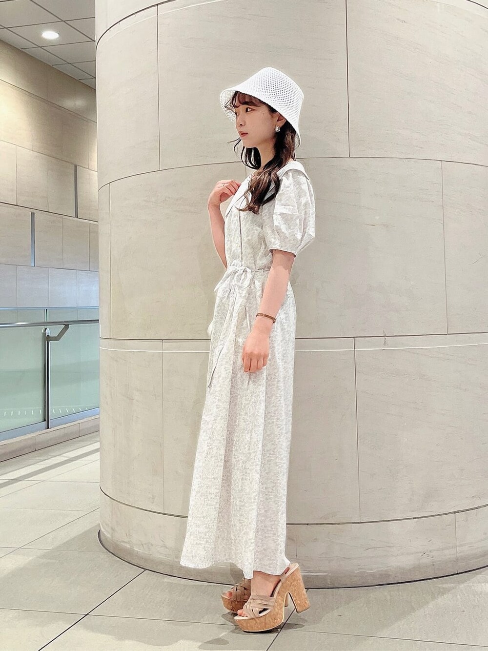 ベージュ系のサンダル、ホワイト系のワンピース、ホワイト系のハットを着用したレディースの春コーディネートの2枚目の写真