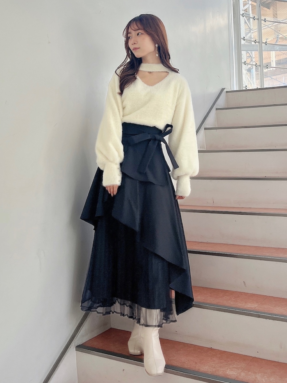 ホワイト系のブーツ、ブラック系のスカート、ホワイト系のニット/セーターを着用したレディースの秋コーディネートの4枚目の写真
