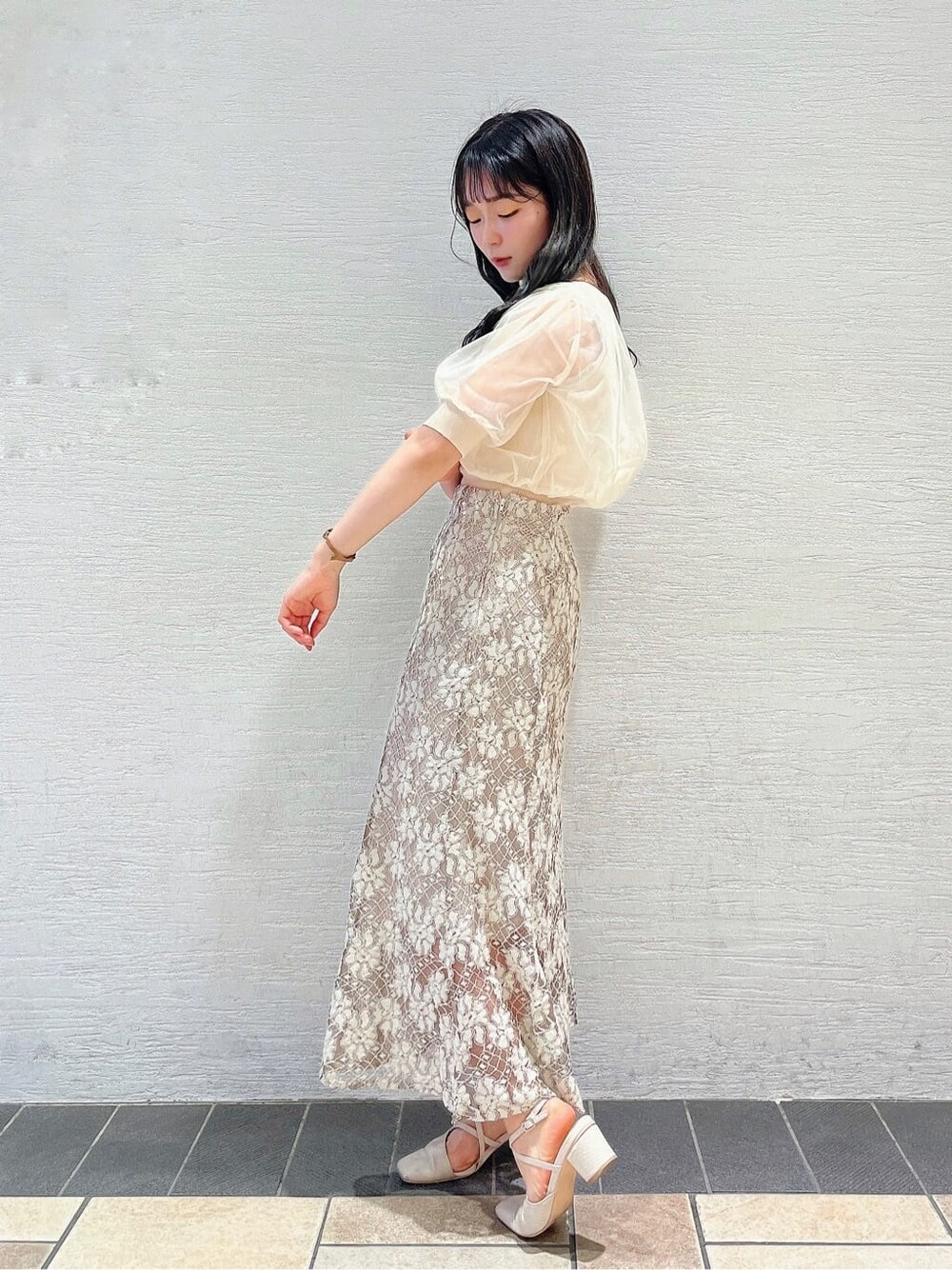 ベージュ系のスカート、ホワイト系のパンプス、ホワイト系のニット/セーターを着用したレディースの春コーディネートの2枚目の写真