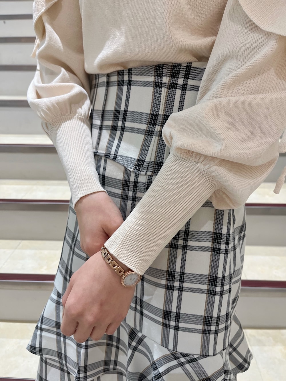 ホワイト系のニット/セーター、ホワイト系のスカート、ベージュ系のブーツを着用したレディースの冬コーディネートの10枚目の写真