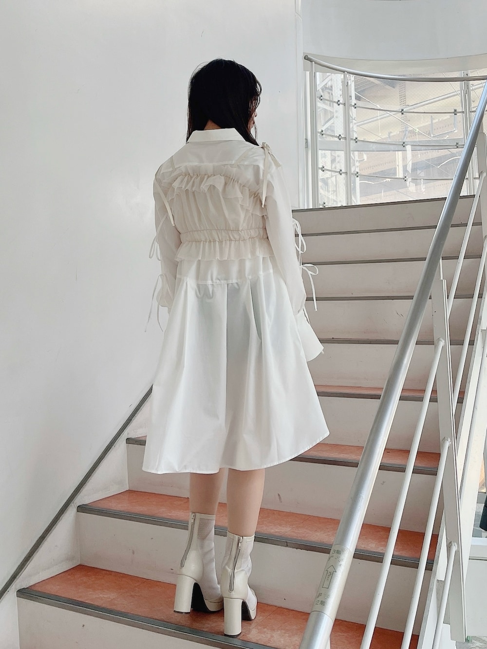 ベージュ系のキャミソール、ホワイト系のシャツワンピース、ホワイト系のブーツを着用したレディースの冬コーディネートの4枚目の写真