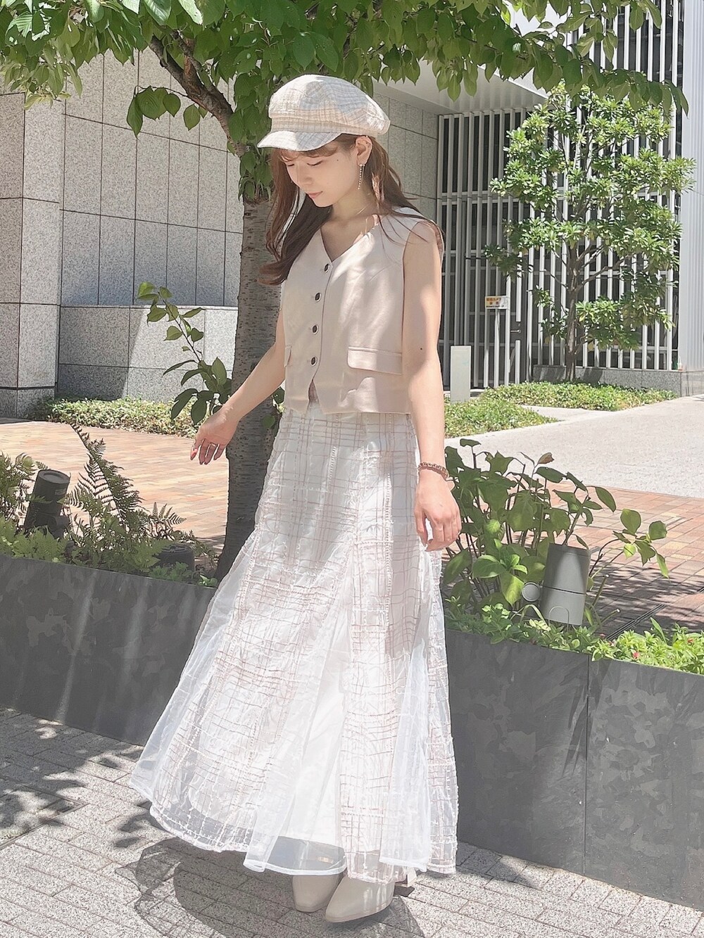 ベージュ系のベスト、ベージュ系のスカート、ホワイト系のローファーを着用したレディースの夏コーディネートの5枚目の写真