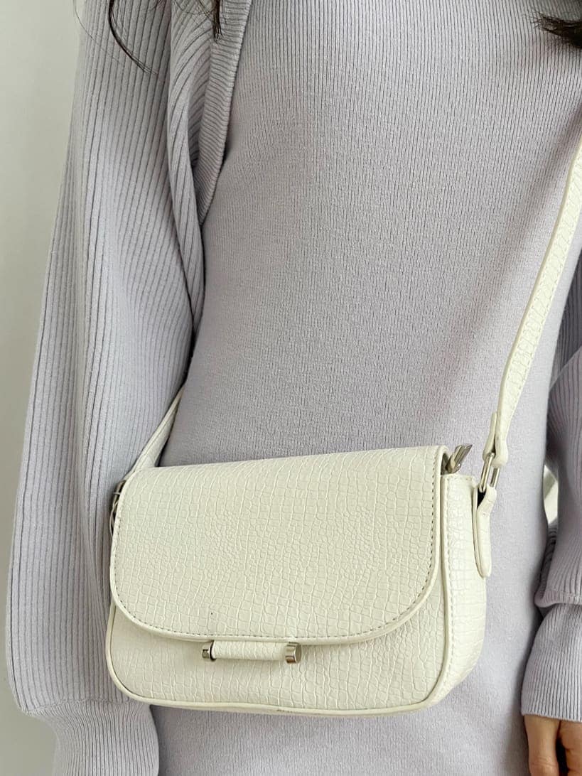 パープル系のワンピース、ブラック系のブーツ、ホワイト系のショルダーバッグを着用したレディースの冬コーディネートの10枚目の写真