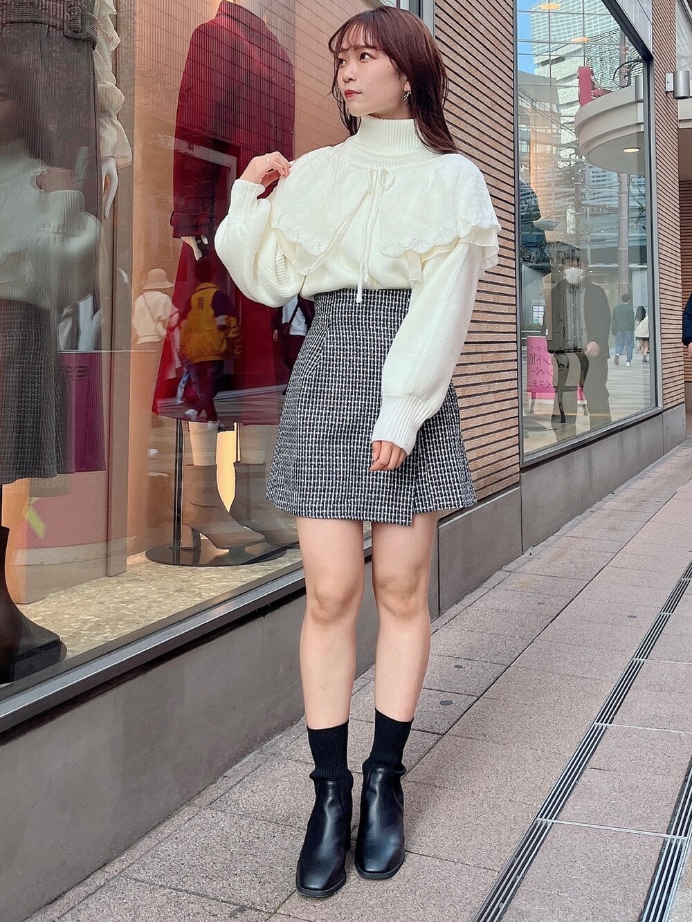 ホワイト系のニット/セーター、ブルー系のスカート、ブラック系のブーツを着用したレディースの秋コーディネートの2枚目の写真