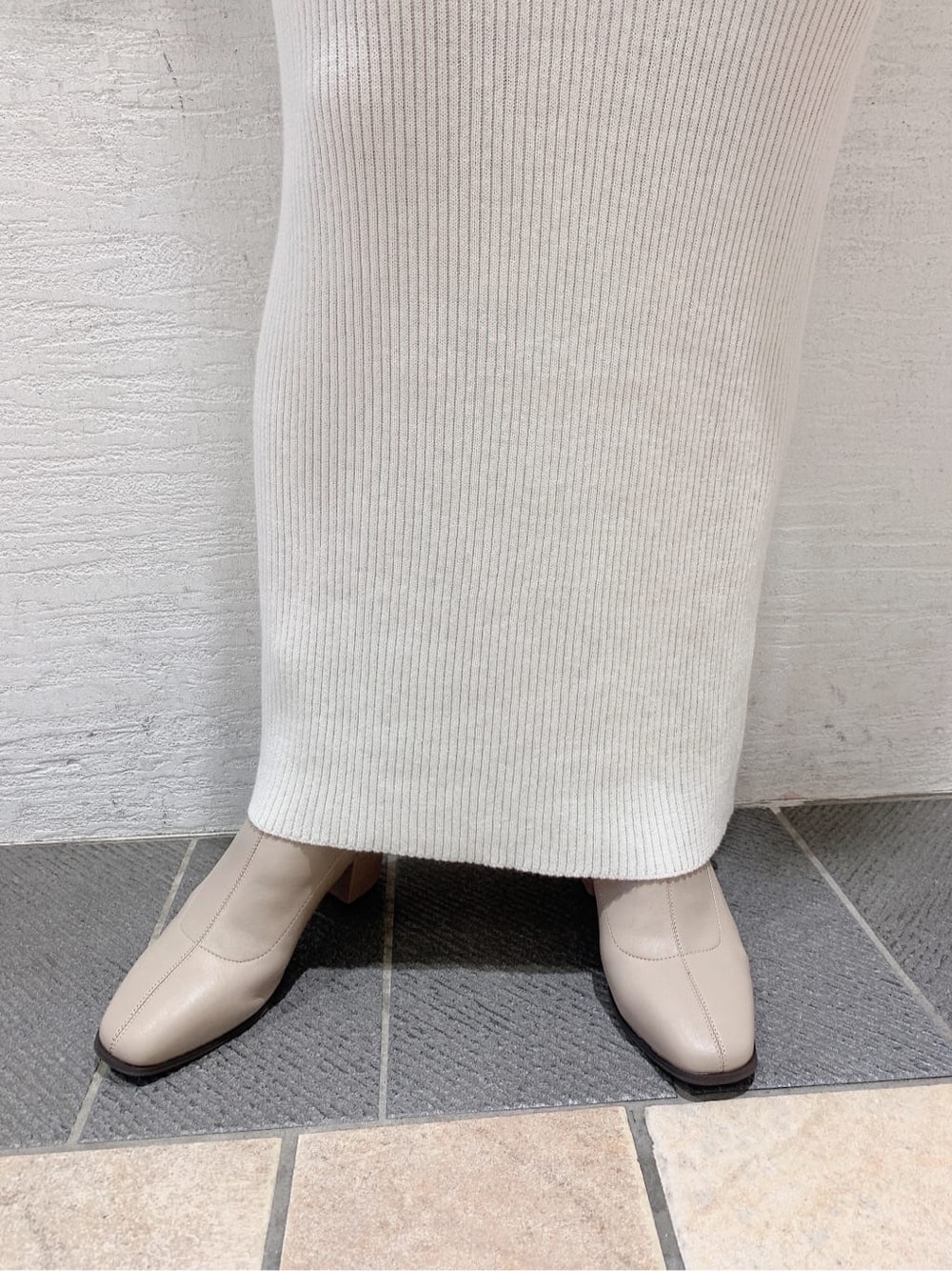 グレー系のブルゾン、ベージュ系のブーツ、ホワイト系のワンピースを着用したレディースの秋コーディネートの5枚目の写真