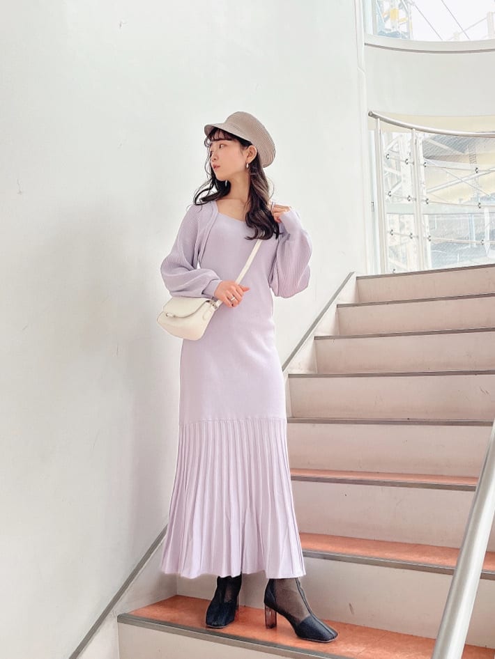 パープル系のワンピース、ブラック系のブーツ、ホワイト系のショルダーバッグを着用したレディースの冬コーディネートの2枚目の写真