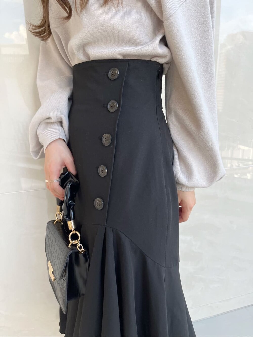 グレー系のニット/セーター、ブラック系のスカート、ブラック系のパンプスを着用したレディースの夏コーディネートの7枚目の写真