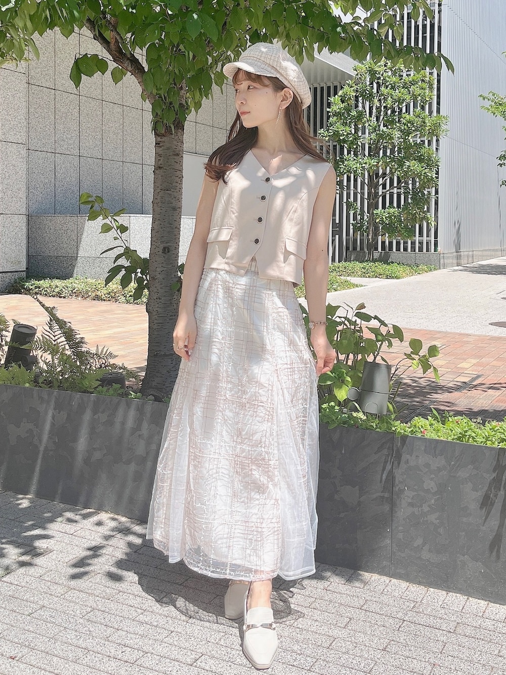 ベージュ系のベスト、ベージュ系のスカート、ホワイト系のローファーを着用したレディースの夏コーディネートの3枚目の写真