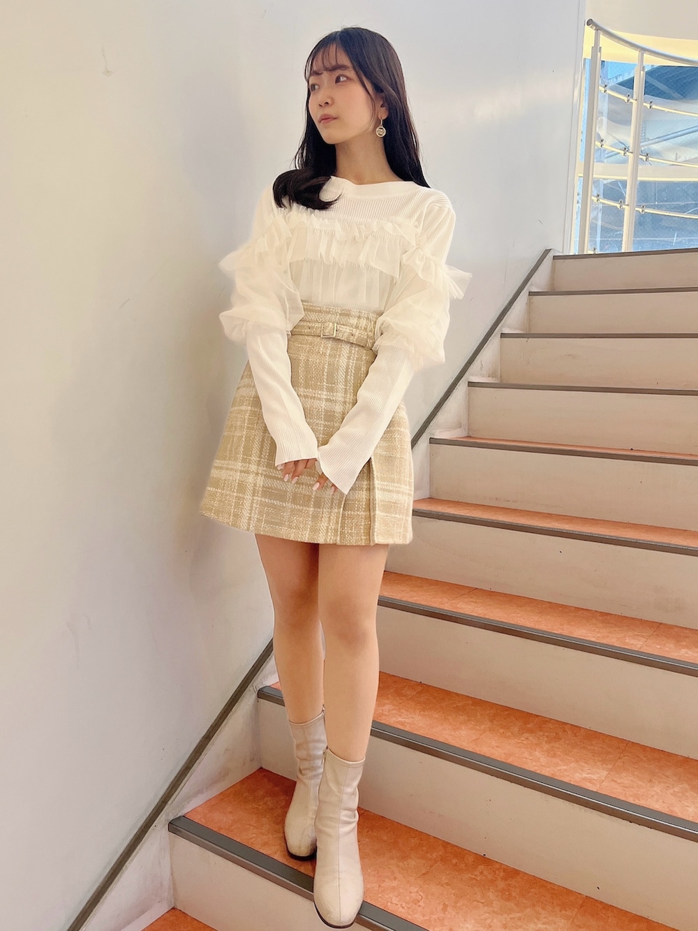 ホワイト系のニット/セーター、ベージュ系のスカート、ベージュ系のブーツを着用したレディースの冬コーディネートの2枚目の写真