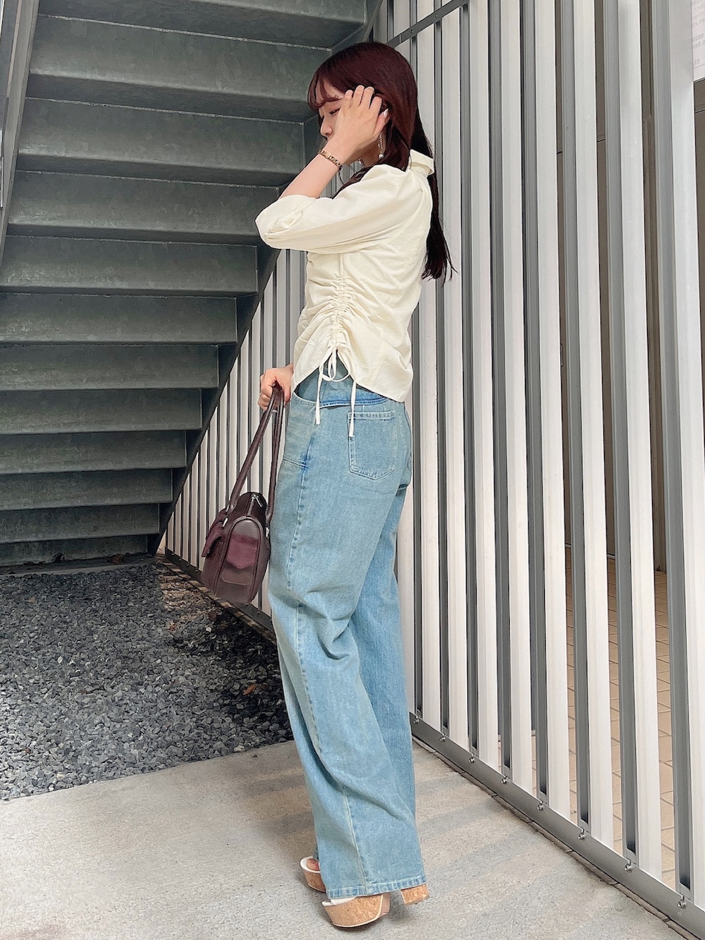 イエロー系のシャツ/ブラウス、ブルー系のデニムパンツ、ブラウン系のボストンバッグを着用したレディースの夏コーディネートの3枚目の写真