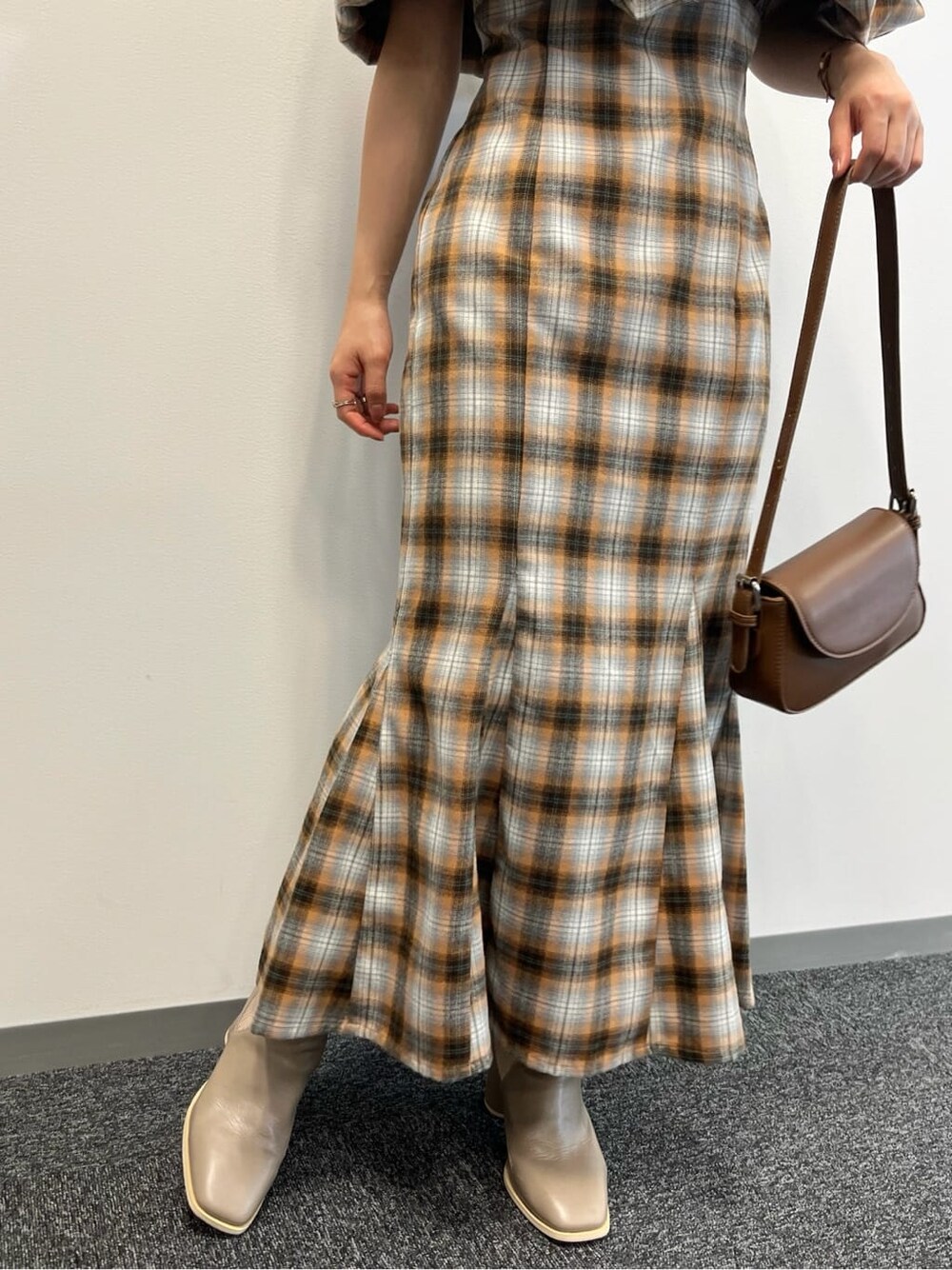 オレンジ系のワンピース、ベージュ系のブーツを着用したレディースの夏コーディネートの9枚目の写真