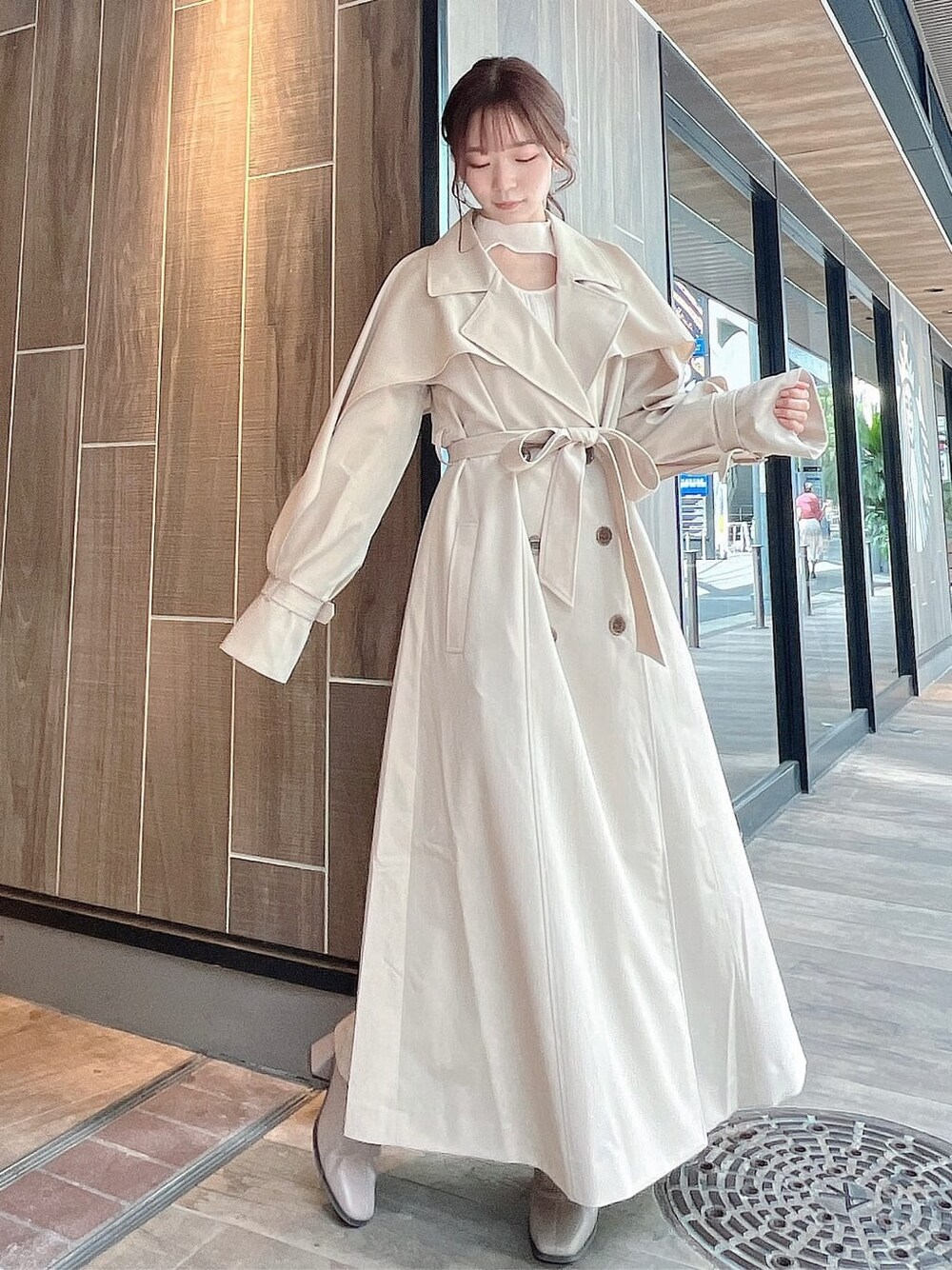 ベージュ系のトレンチコート、ベージュ系のブーツ、ベージュ系のスカートを着用したレディースの秋コーディネートの3枚目の写真