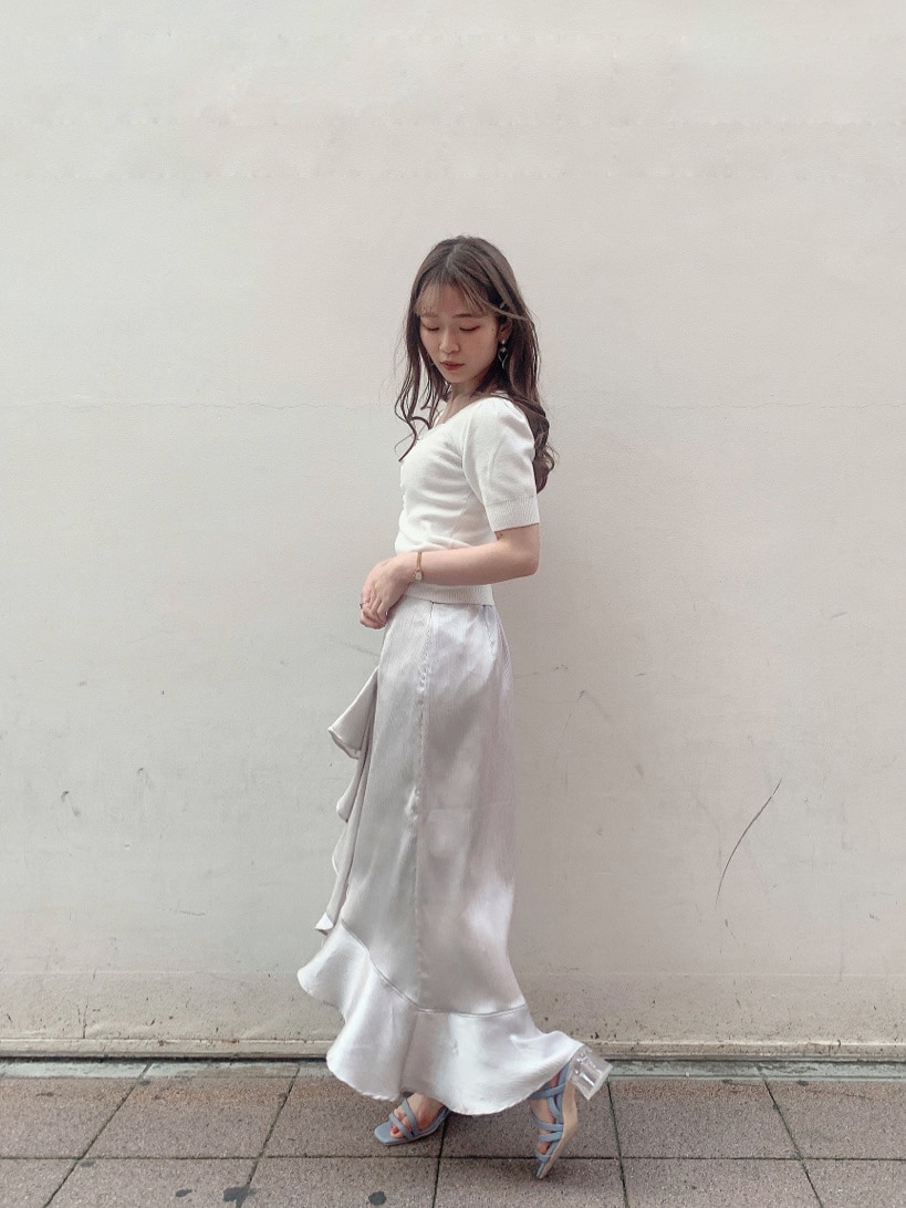 グレー系のスカート、ブルー系のサンダル、ホワイト系のニット/セーターを着用したレディースの春コーディネートの2枚目の写真