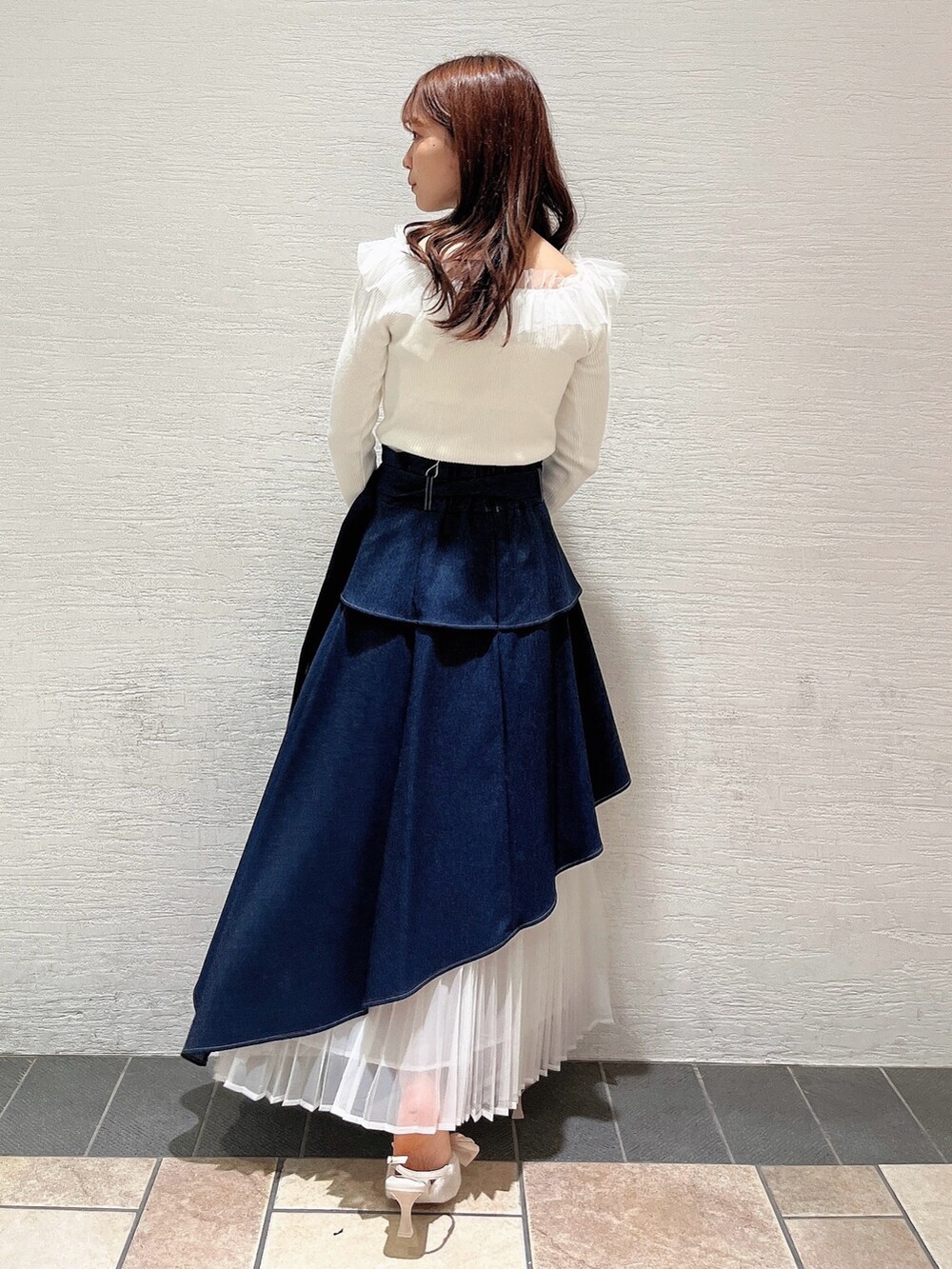 ベージュ系のパンプス、ブルー系のスカート、ホワイト系のニット/セーターを着用したレディースの秋コーディネートの4枚目の写真