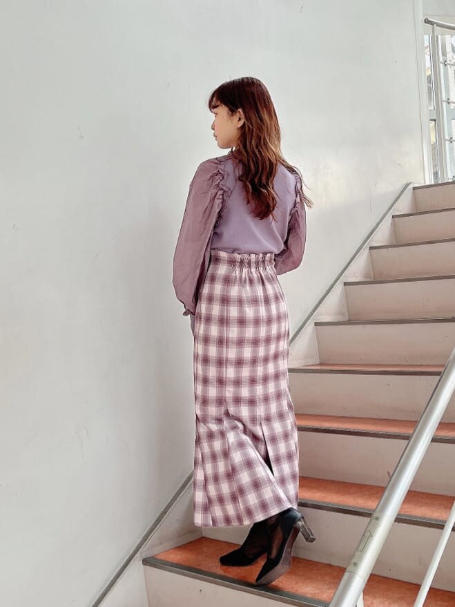 ブラック系のブーツ、パープル系のニット/セーター、パープル系のスカートを着用したレディースの冬コーディネートの2枚目の写真