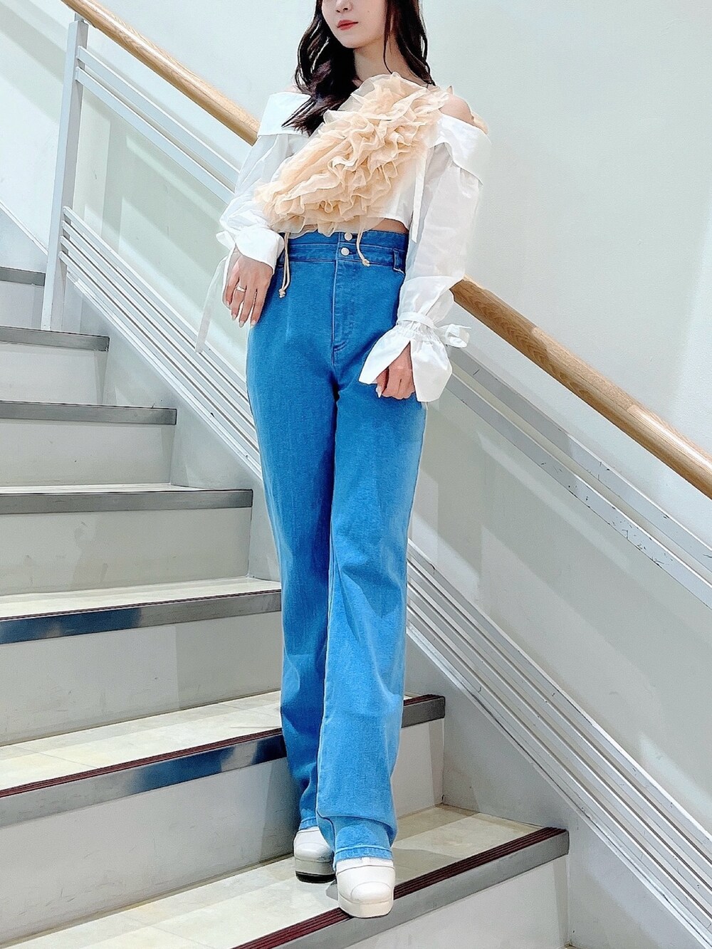 オレンジ系のベスト、ブルー系のデニムパンツ、ホワイト系のシャツ/ブラウスを着用したレディースの春コーディネートの5枚目の写真