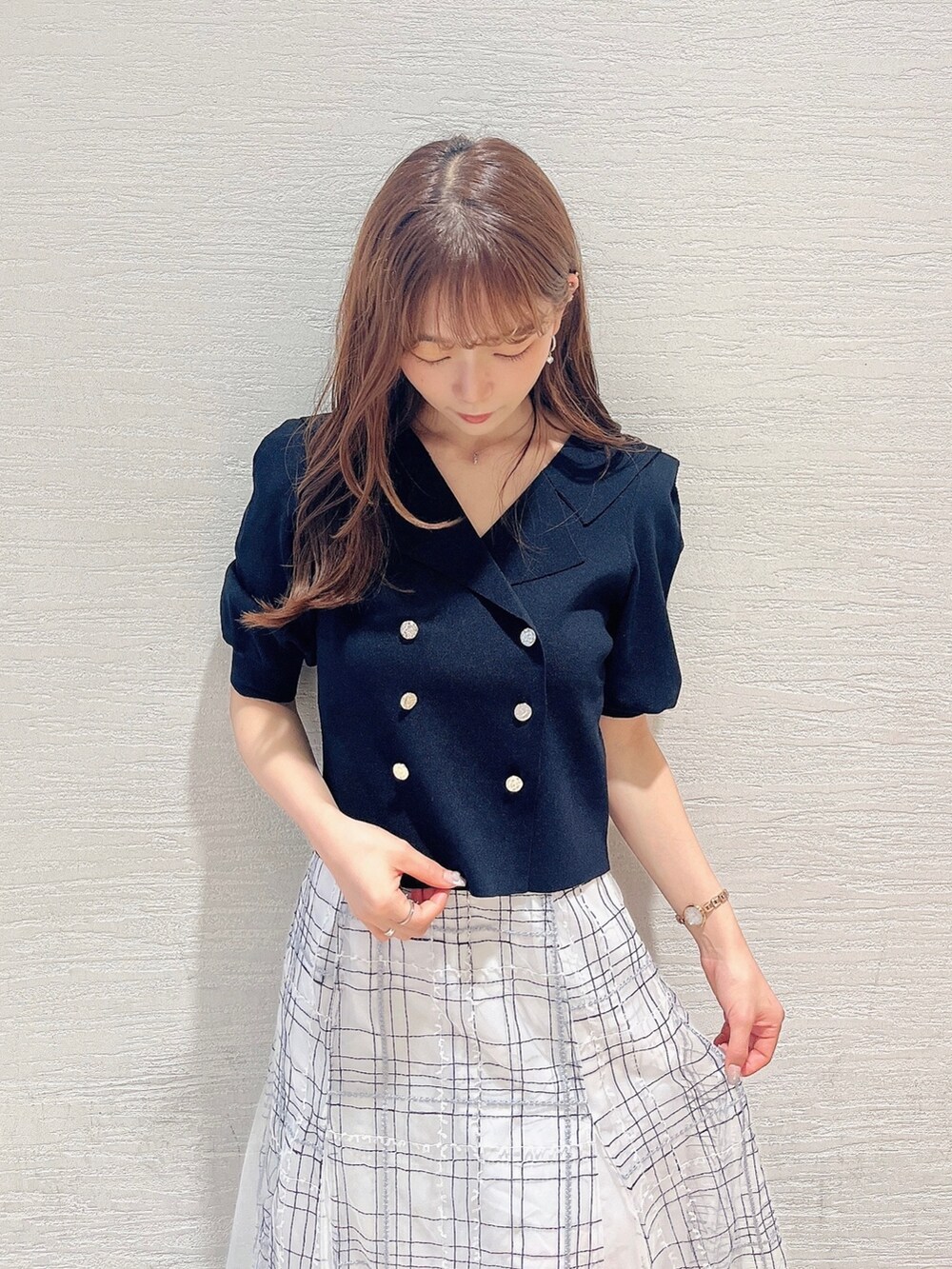 ブラック系のニット/セーター、ホワイト系のスカート、ブラック系のローファーを着用したレディースの夏コーディネートの5枚目の写真