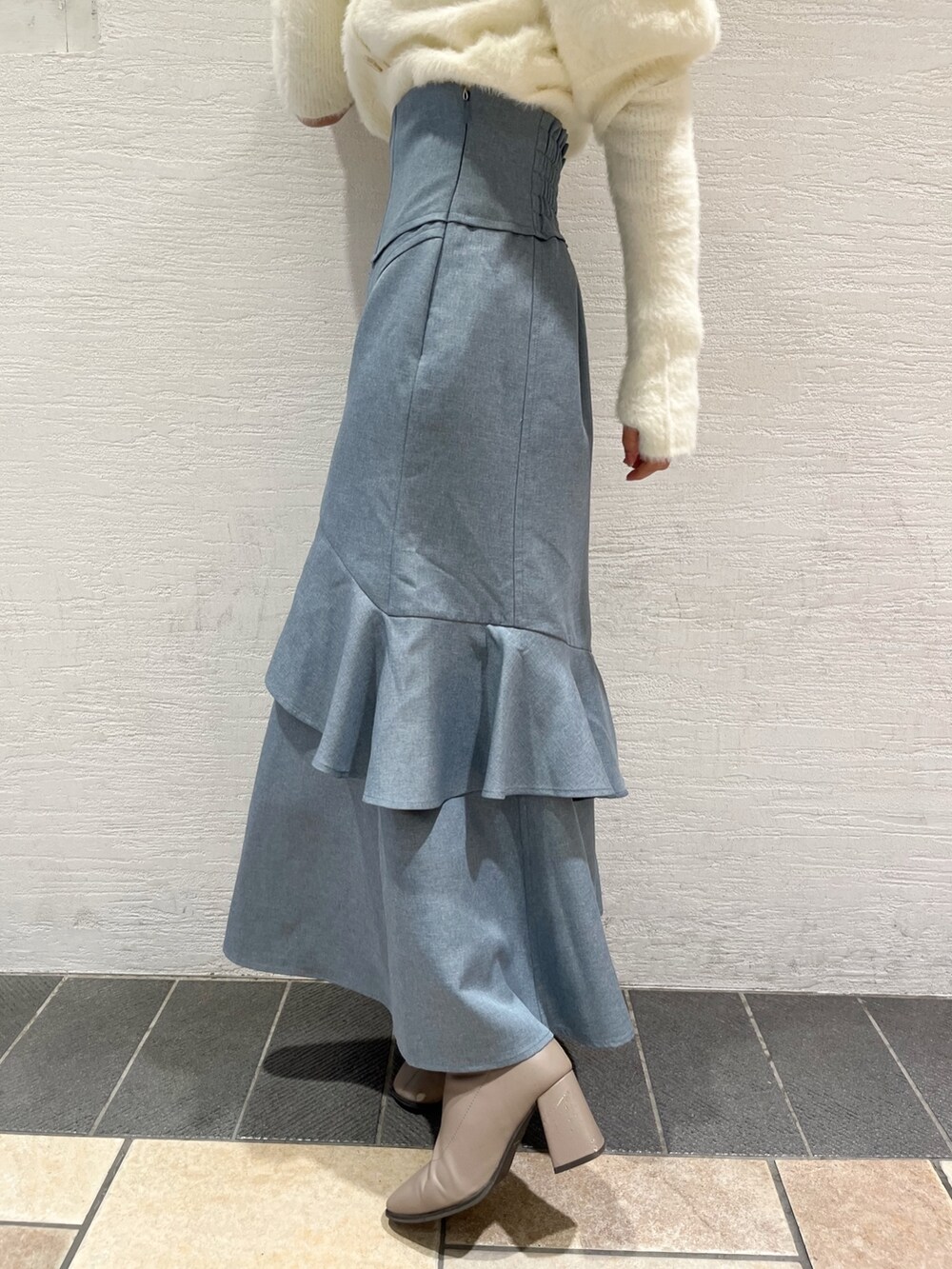 ホワイト系のニット/セーター、ブルー系のスカート、ベージュ系のブーツを着用したレディースの冬コーディネートの9枚目の写真