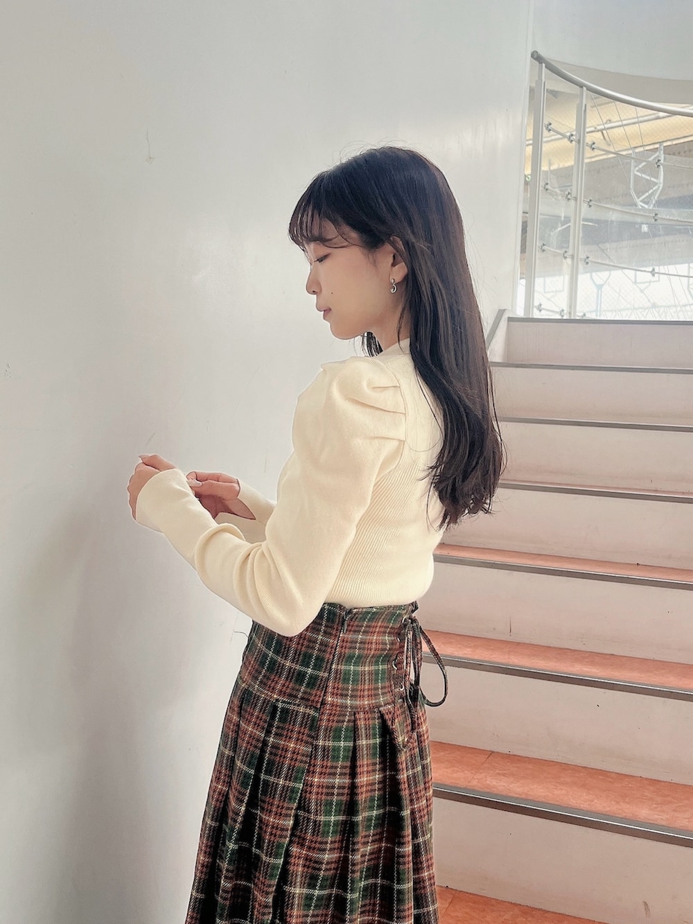 ホワイト系のニット/セーター、グリーン系のスカート、ベージュ系のブーツを着用したレディースの秋コーディネートの7枚目の写真