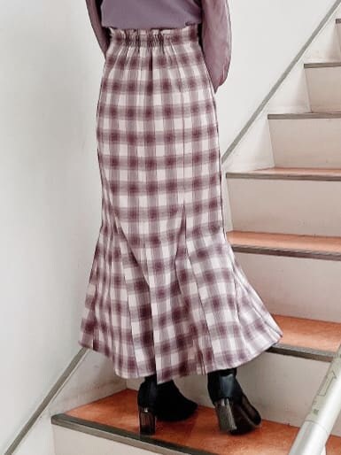 ブラック系のブーツ、パープル系のニット/セーター、パープル系のスカートを着用したレディースの冬コーディネートの9枚目の写真