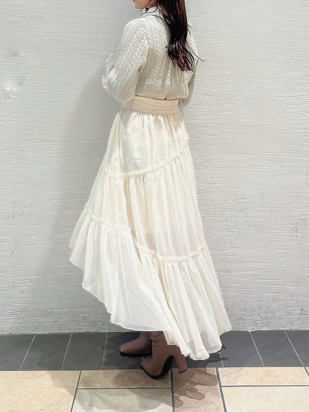 ベージュ系のニット/セーター、ホワイト系のスカート、ベージュ系のブーツを着用したレディースの冬コーディネートの3枚目の写真