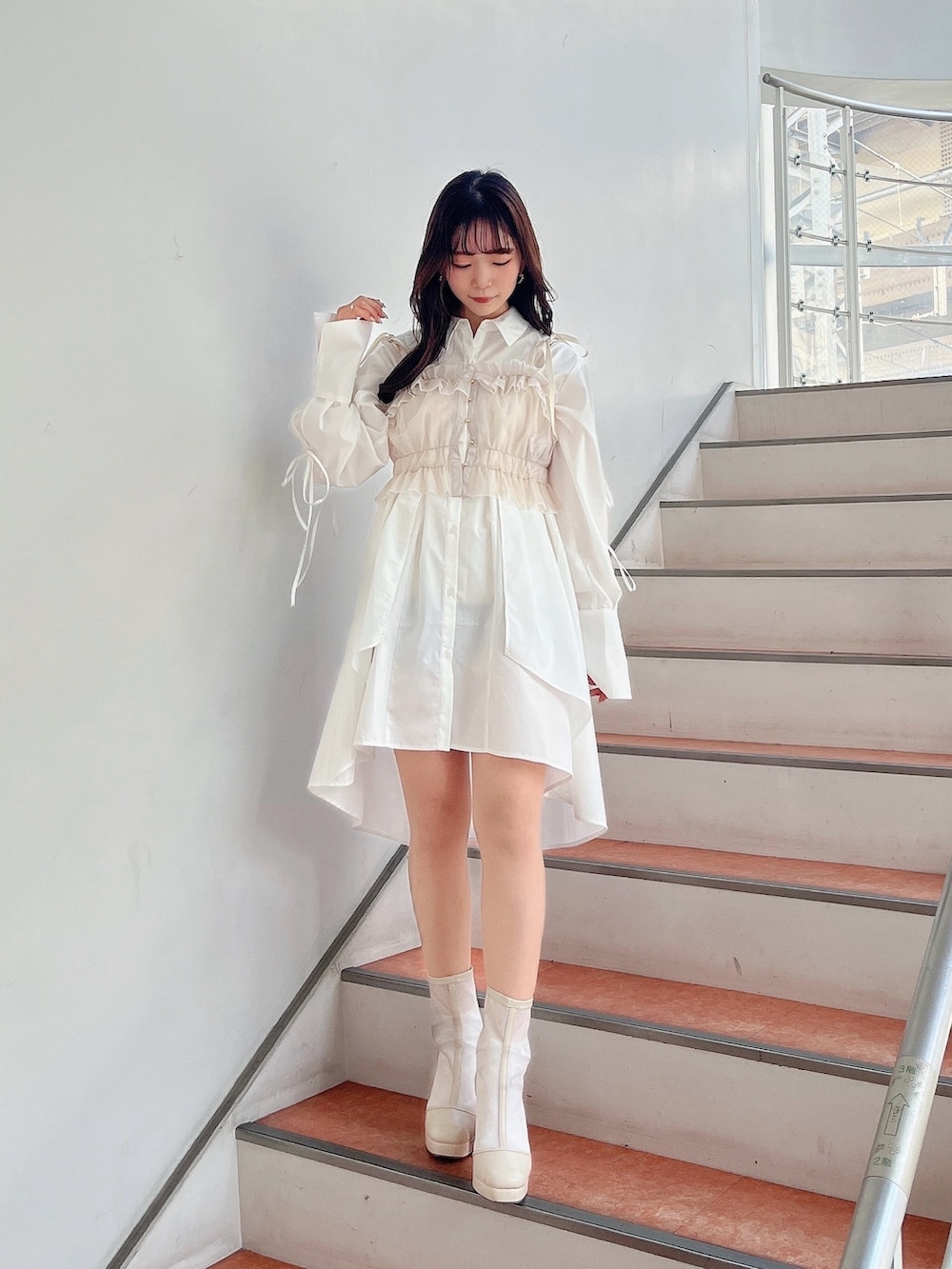 ベージュ系のキャミソール、ホワイト系のシャツワンピース、ホワイト系のブーツを着用したレディースの冬コーディネートの5枚目の写真