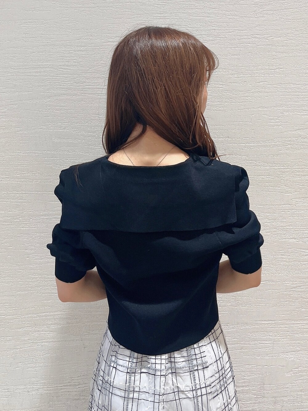 ブラック系のニット/セーター、ホワイト系のスカート、ブラック系のローファーを着用したレディースの夏コーディネートの7枚目の写真