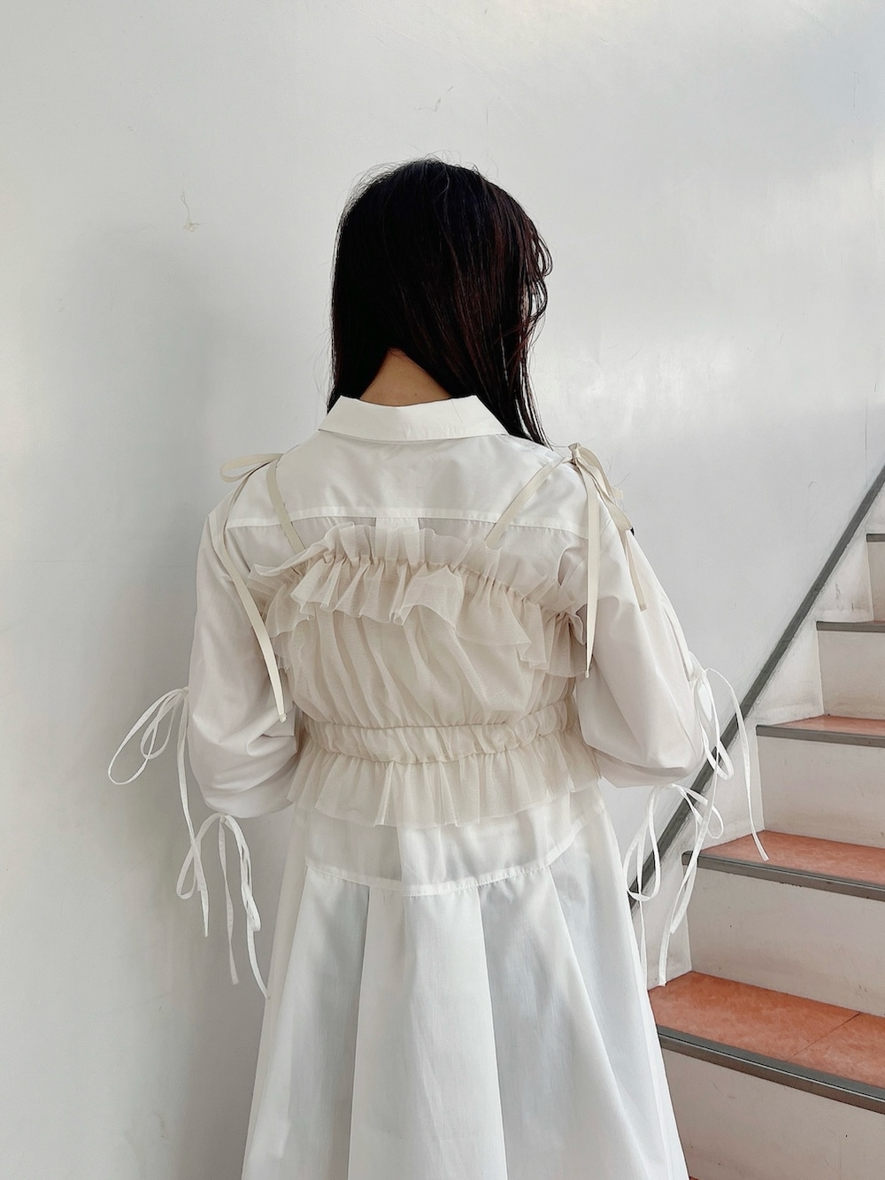 ベージュ系のキャミソール、ホワイト系のシャツワンピース、ホワイト系のブーツを着用したレディースの冬コーディネートの8枚目の写真