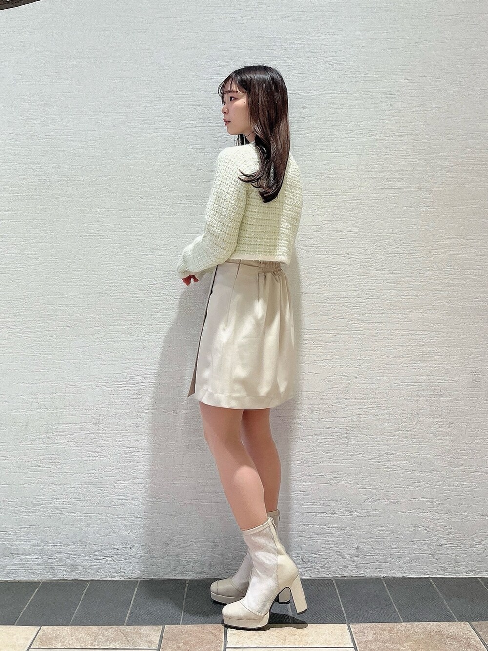 グリーン系のノーカラージャケット、ホワイト系のブーツ、ホワイト系のスカートを着用したレディースの冬コーディネートの4枚目の写真