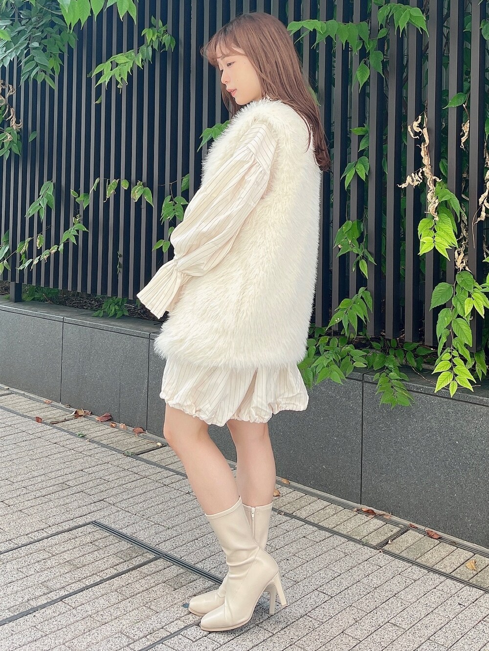 ホワイト系のベスト、ベージュ系のワンピース、ホワイト系のブーツを着用したレディースの秋コーディネートの3枚目の写真