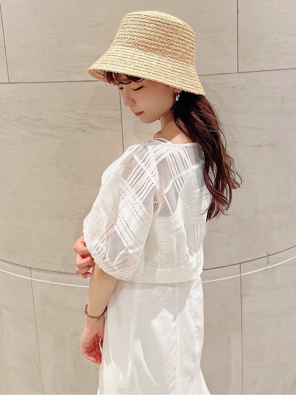 ホワイト系のワンピース、ホワイト系のサンダル、ベージュ系のハットを着用したレディースの夏コーディネートの5枚目の写真