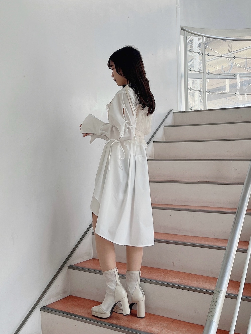 ベージュ系のキャミソール、ホワイト系のシャツワンピース、ホワイト系のブーツを着用したレディースの冬コーディネートの3枚目の写真