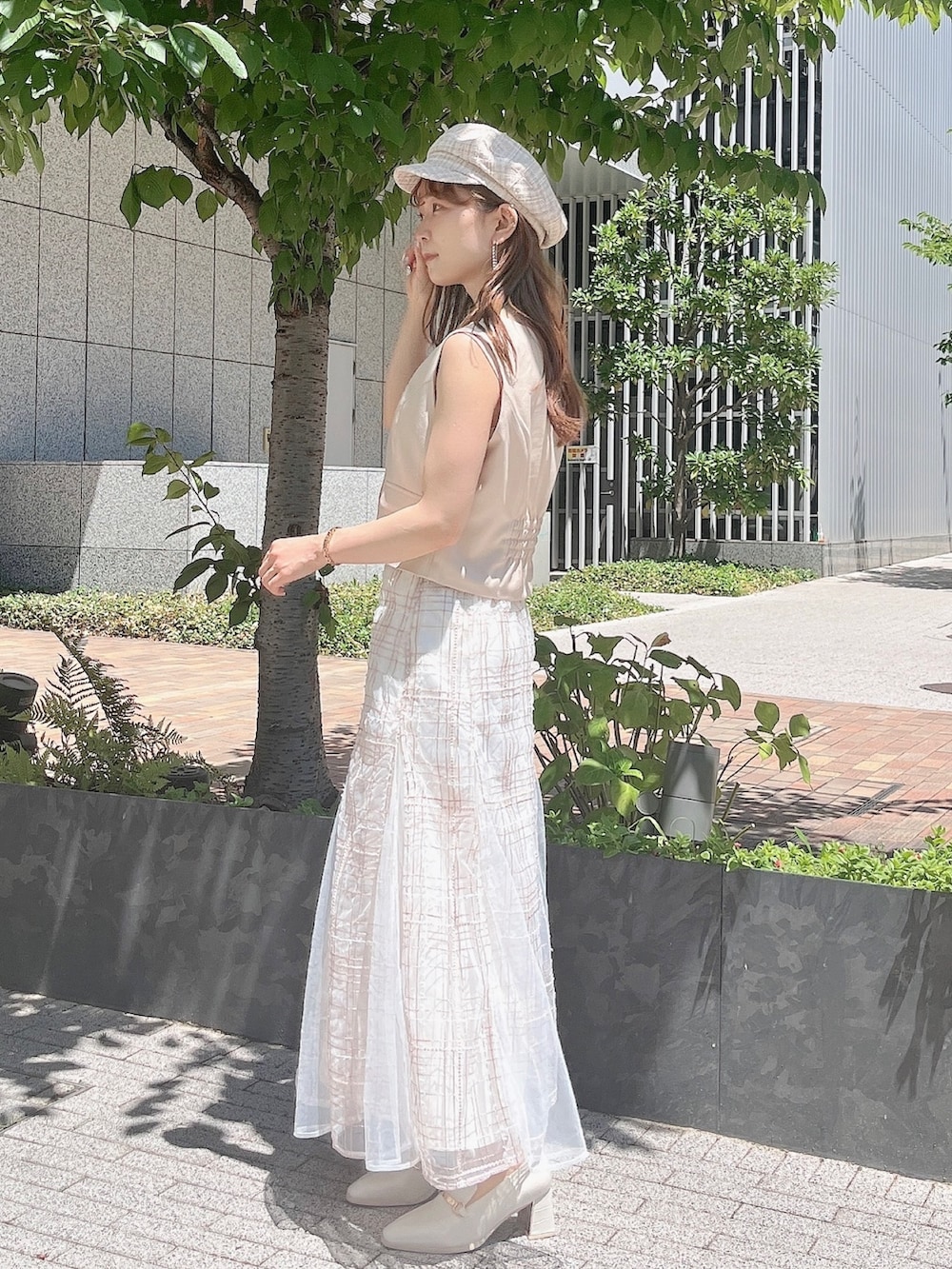 ベージュ系のベスト、ベージュ系のスカート、ホワイト系のローファーを着用したレディースの夏コーディネートの4枚目の写真