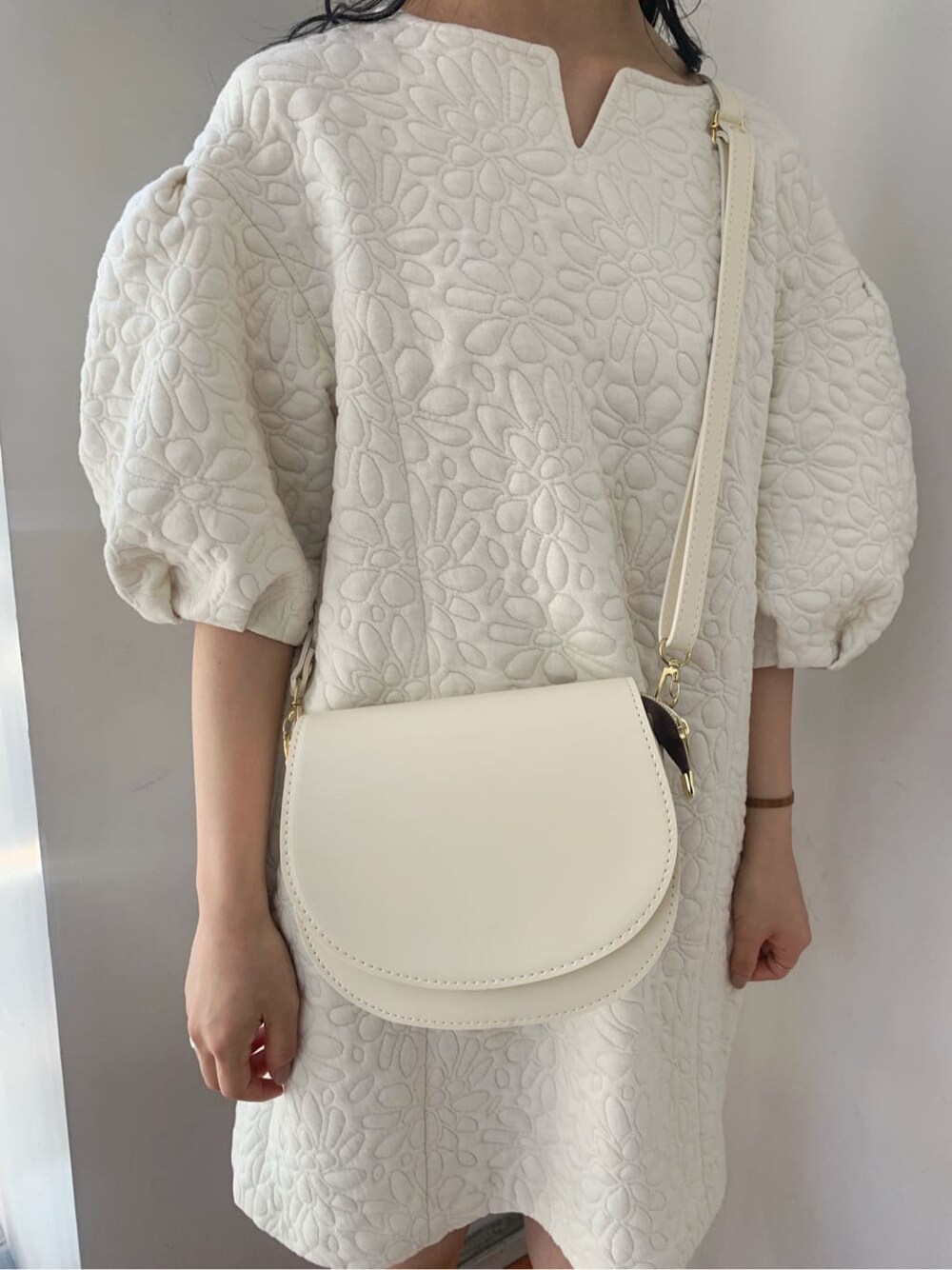 ホワイト系のチュニック、ベージュ系のショルダーバッグ、ベージュ系のブーツを着用したレディースの秋コーディネートの7枚目の写真