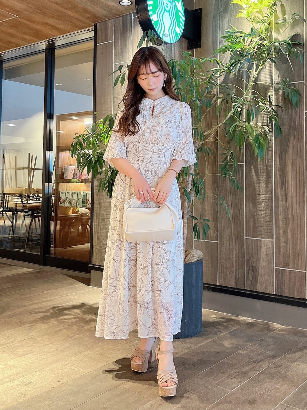 ベージュ系のサンダル、ホワイト系のハンドバッグ、ホワイト系のワンピースを着用したレディースの春コーディネートの2枚目の写真