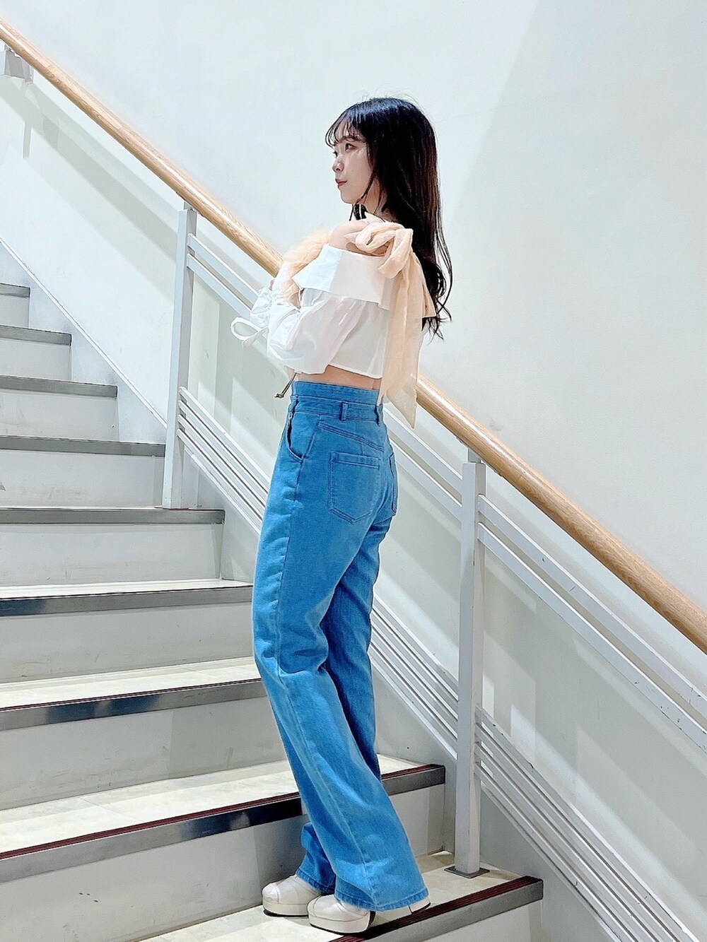 オレンジ系のベスト、ブルー系のデニムパンツ、ホワイト系のシャツ/ブラウスを着用したレディースの春コーディネートの2枚目の写真