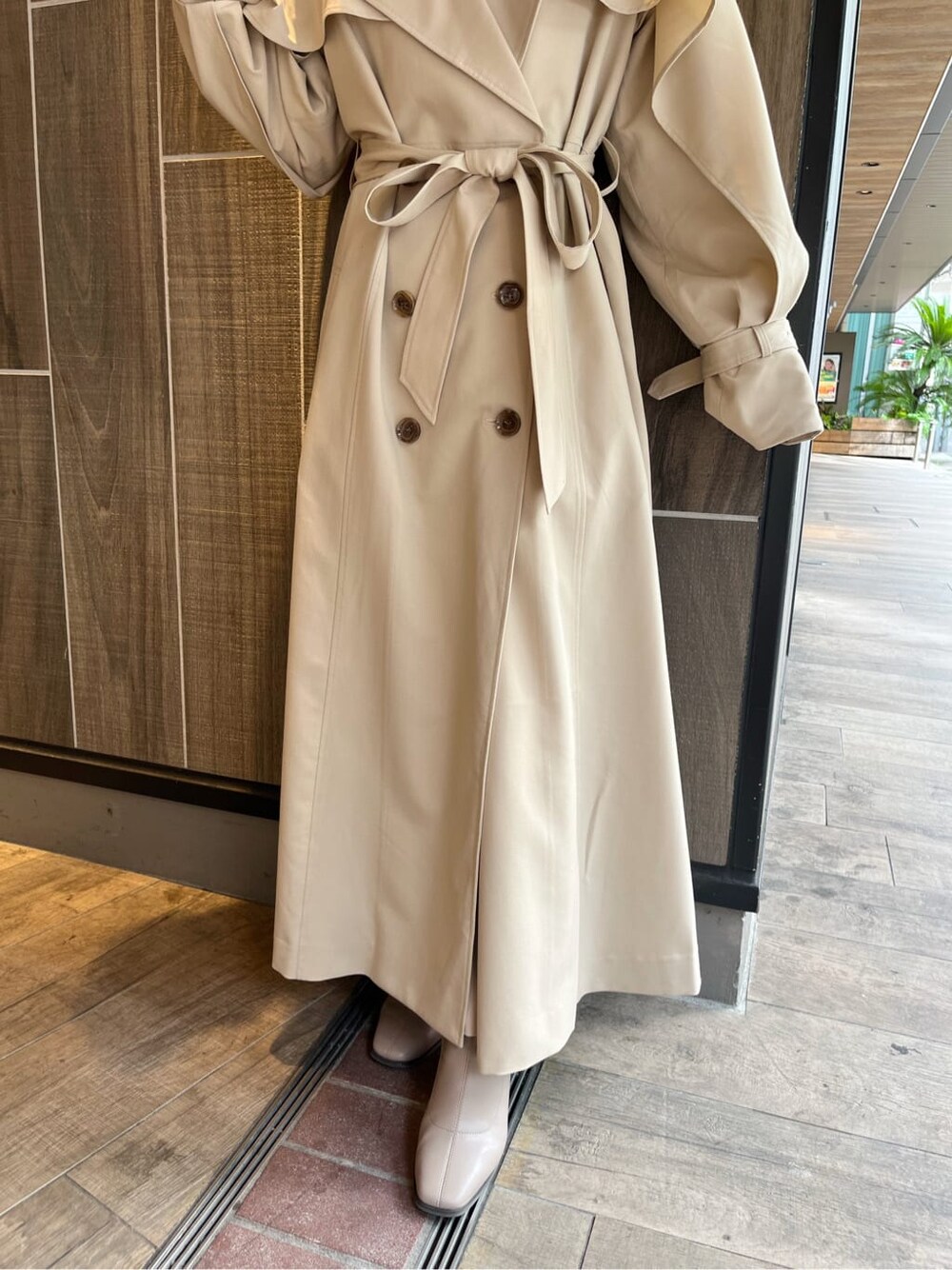 ベージュ系のトレンチコート、ベージュ系のブーツ、ベージュ系のスカートを着用したレディースの秋コーディネートの8枚目の写真