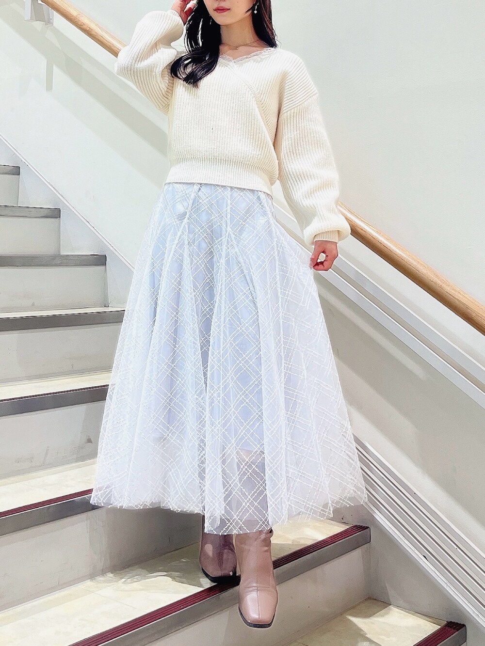 ホワイト系のニット/セーター、グレー系のスカート、ベージュ系のブーツを着用したレディースの冬コーディネートの2枚目の写真